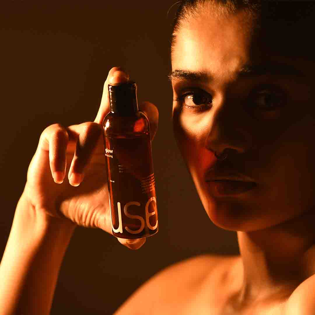 A person holding Glow Relaxing massage oil onto their hands in a dark-lit room