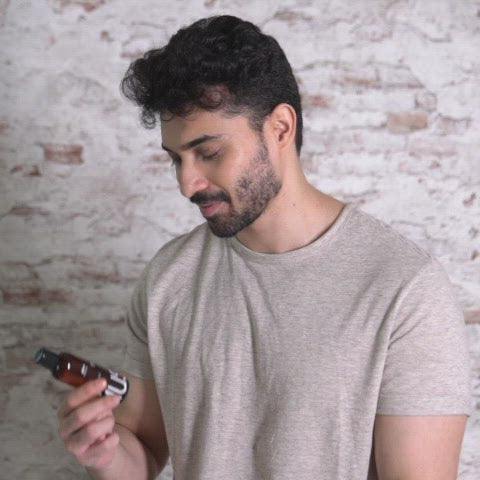 A man is holding a bottle of MyMuse's Glow Relaxing Massage Oil, then pours the oil on a lady's shoulder and massages it